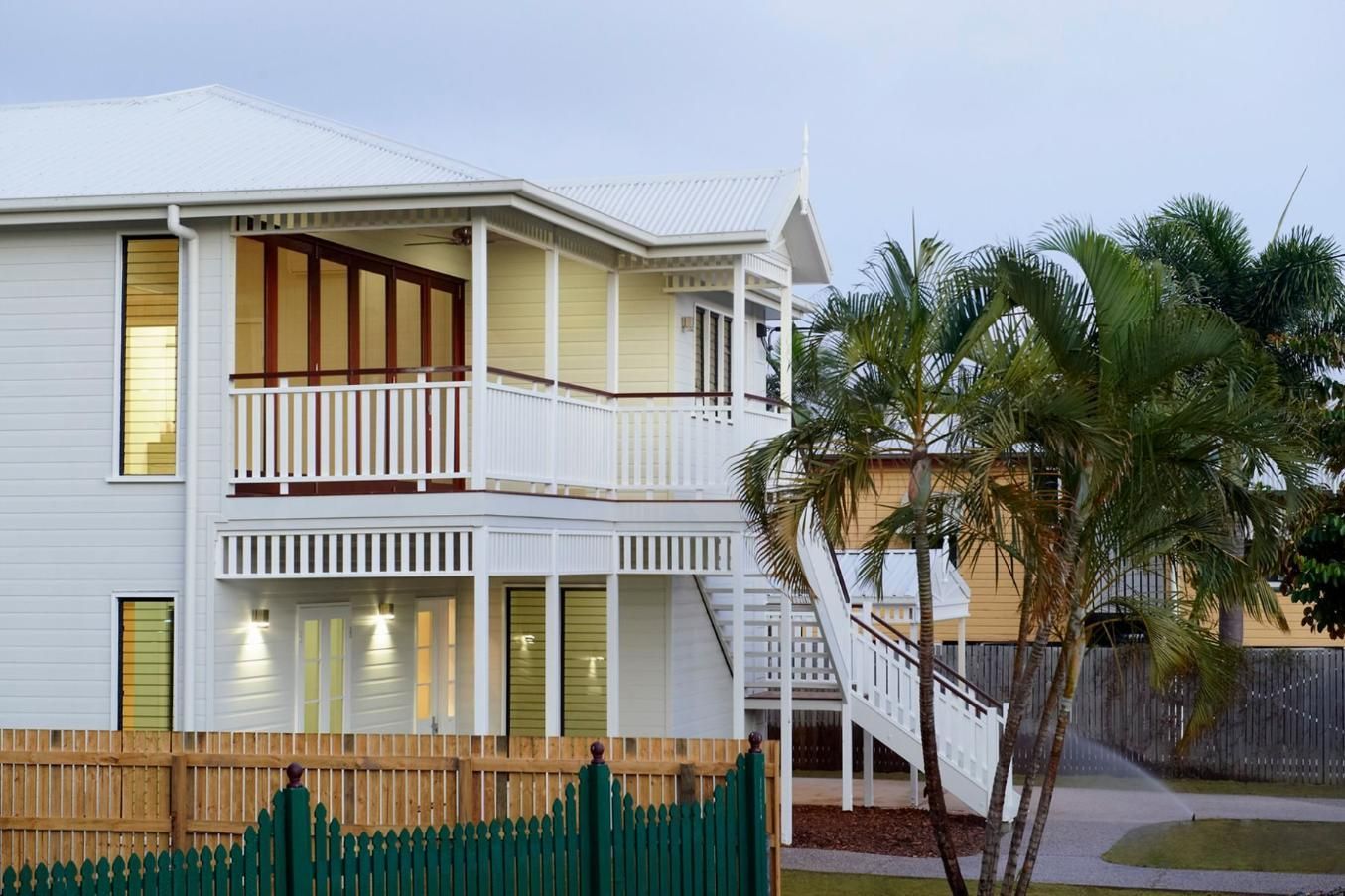 A White House With a Green Fence and a Palm Tree in Front of It — Pro-Jax Pty Ltd in Bohle, QLD