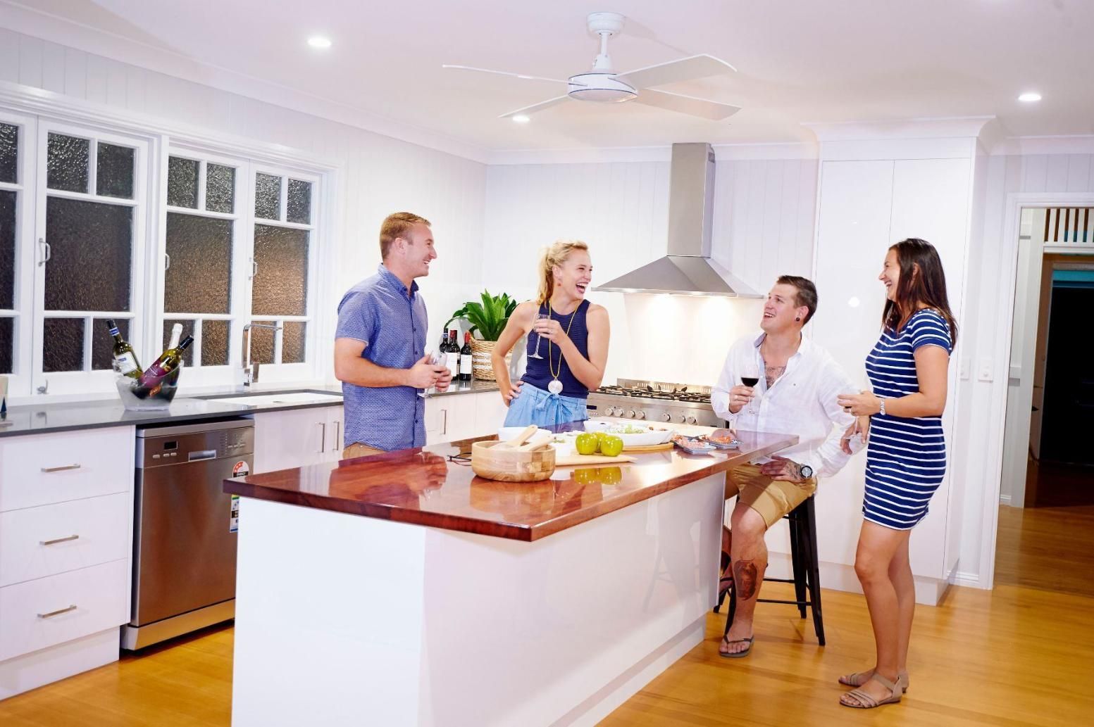 A Group of People Are Standing in a Kitchen Drinking Wine — Pro-Jax Pty Ltd in Bohle, QLD