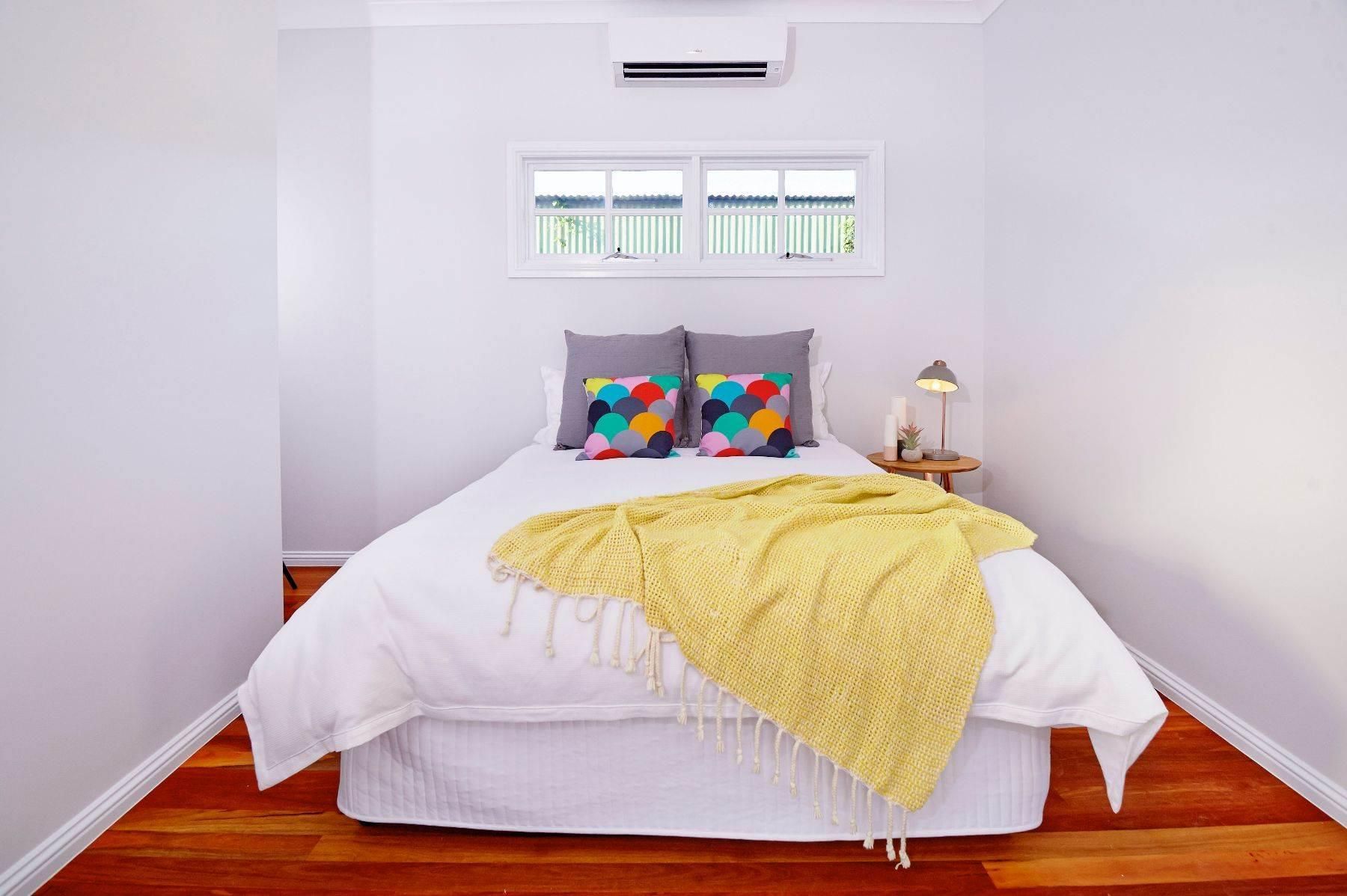 A Bedroom With a Bed and a Window With a Yellow Blanket on It — Pro-Jax Pty Ltd in Bohle, QLD