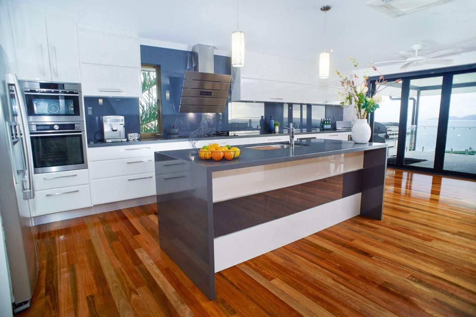 A Kitchen With a Large Island and Hardwood Floors — Pro-Jax Pty Ltd in Bohle, QLD