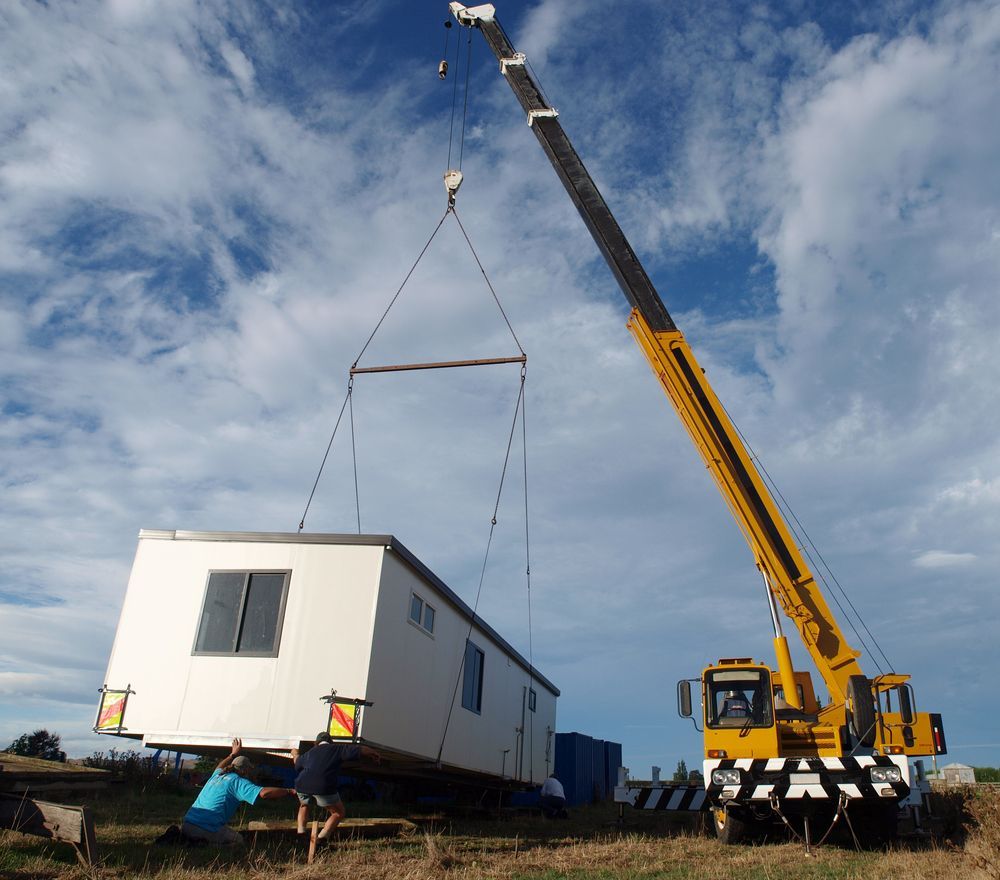 A Yellow Crane Lifting a White Modular Building Into the Air — Pro-Jax Pty Ltd in Bohle, QLD