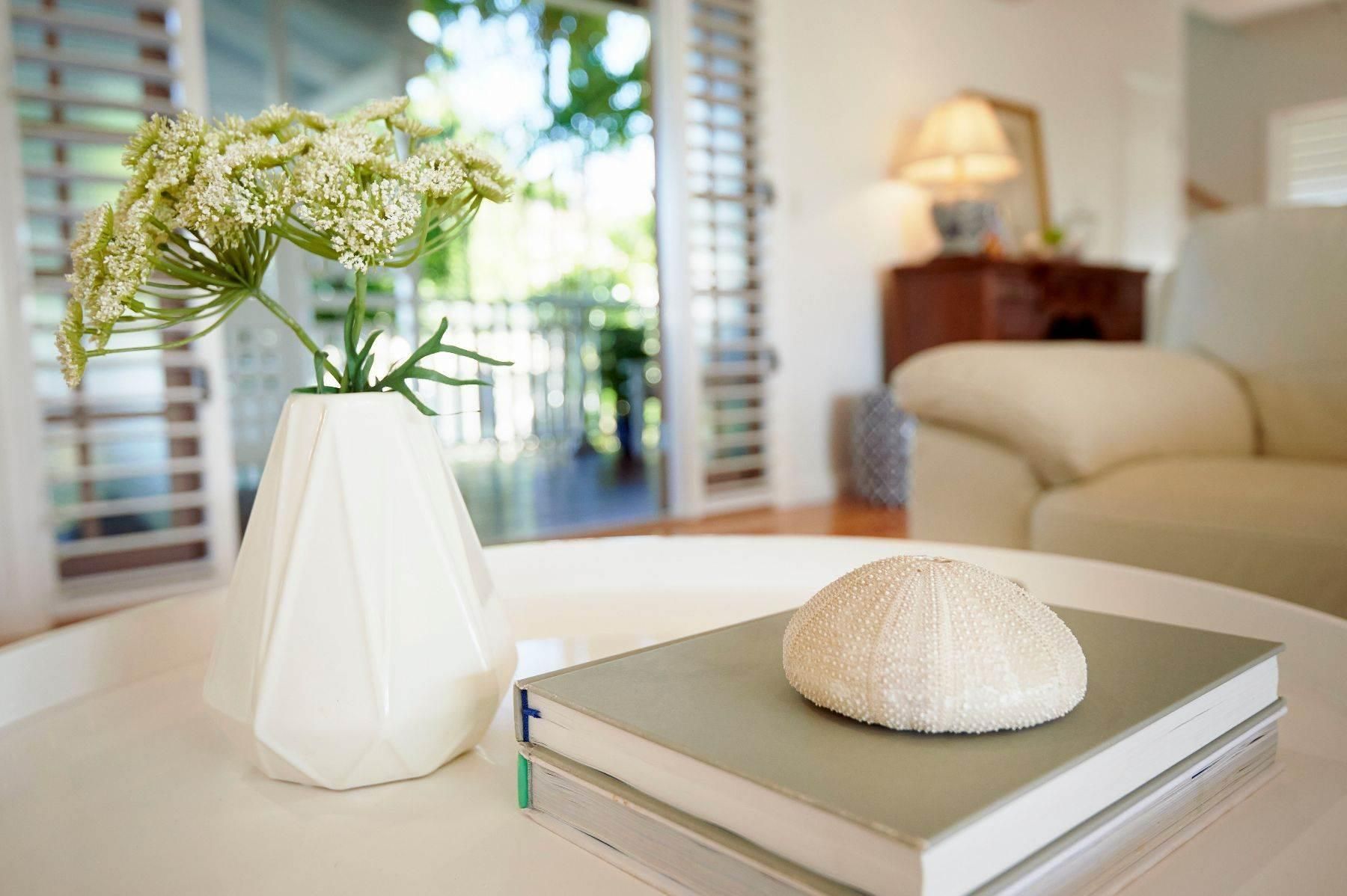 A Vase of Flowers Sits on a Table Next to a Stack of Books — Pro-Jax Pty Ltd in Bohle, QLD
