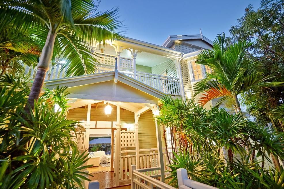 The House is Surrounded by Palm Trees and Plants and is Lit Up at Night — Pro-Jax Pty Ltd in Bohle, QLD