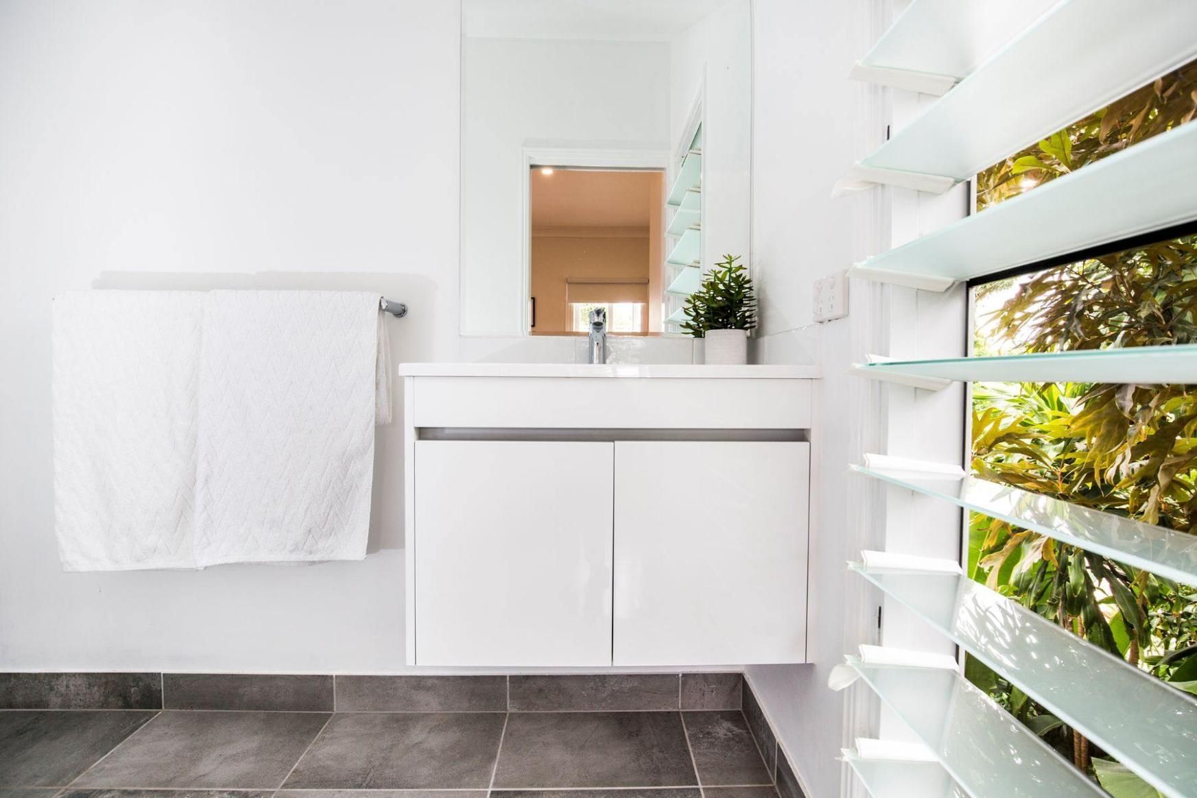 A Bathroom With a Sink, Mirror and Towel Rack — Pro-Jax Pty Ltd in Bohle, QLD