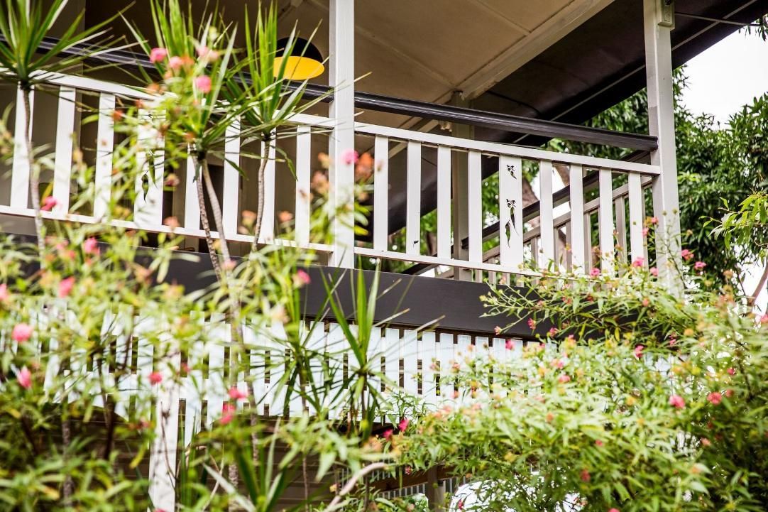 A White Railing on a Porch of a House Surrounded by Plants and Flowers — Pro-Jax Pty Ltd in Bohle, QLD