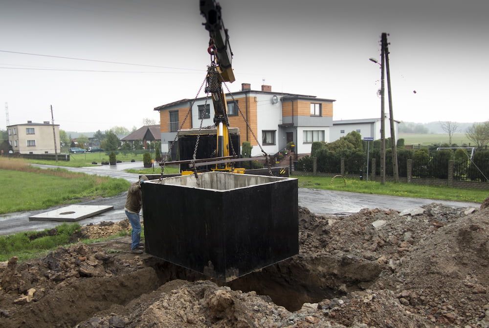 A Crane Lowers a Large, Dark Rectangular Tank Into a Hole — Pro-Jax Pty Ltd in Bohle, QLD