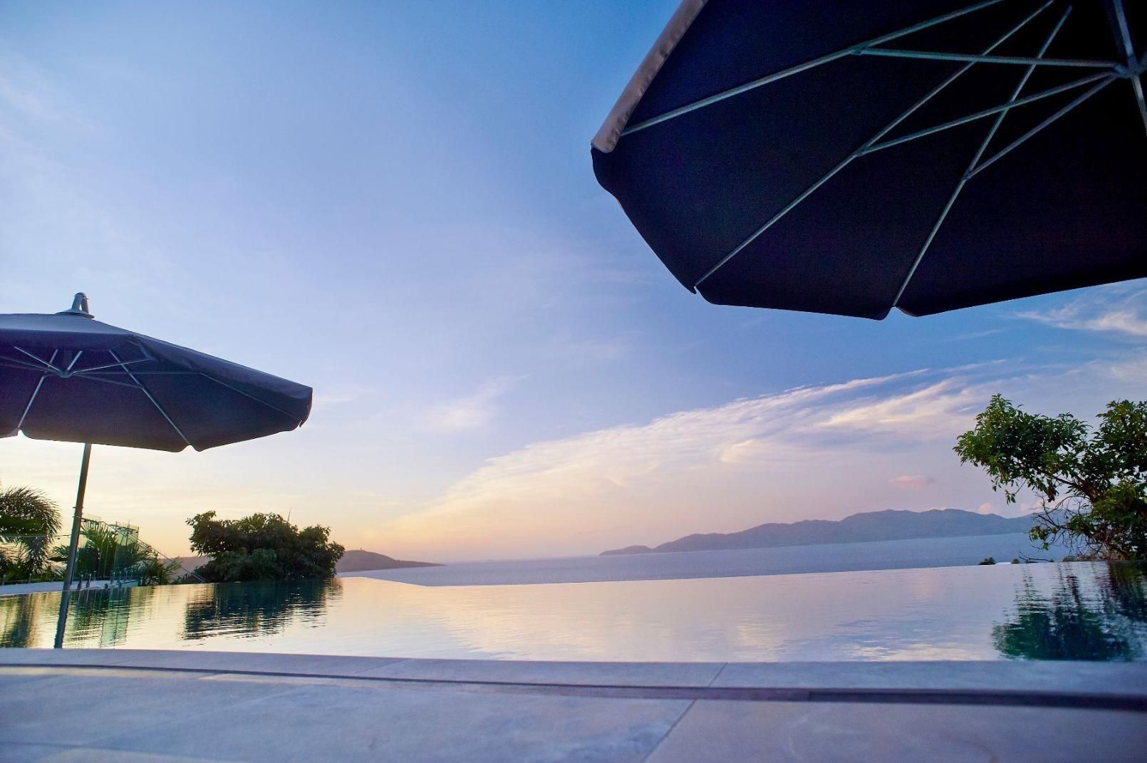 Two Umbrellas Are Sitting Next to a Swimming Pool Overlooking the Ocean — Pro-Jax Pty Ltd in Bohle, QLD