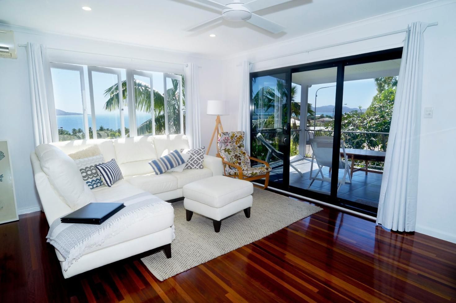 A Living Room With a Couch, Chair, Ottoman and Sliding Glass Doors — Pro-Jax Pty Ltd in Bohle, QLD