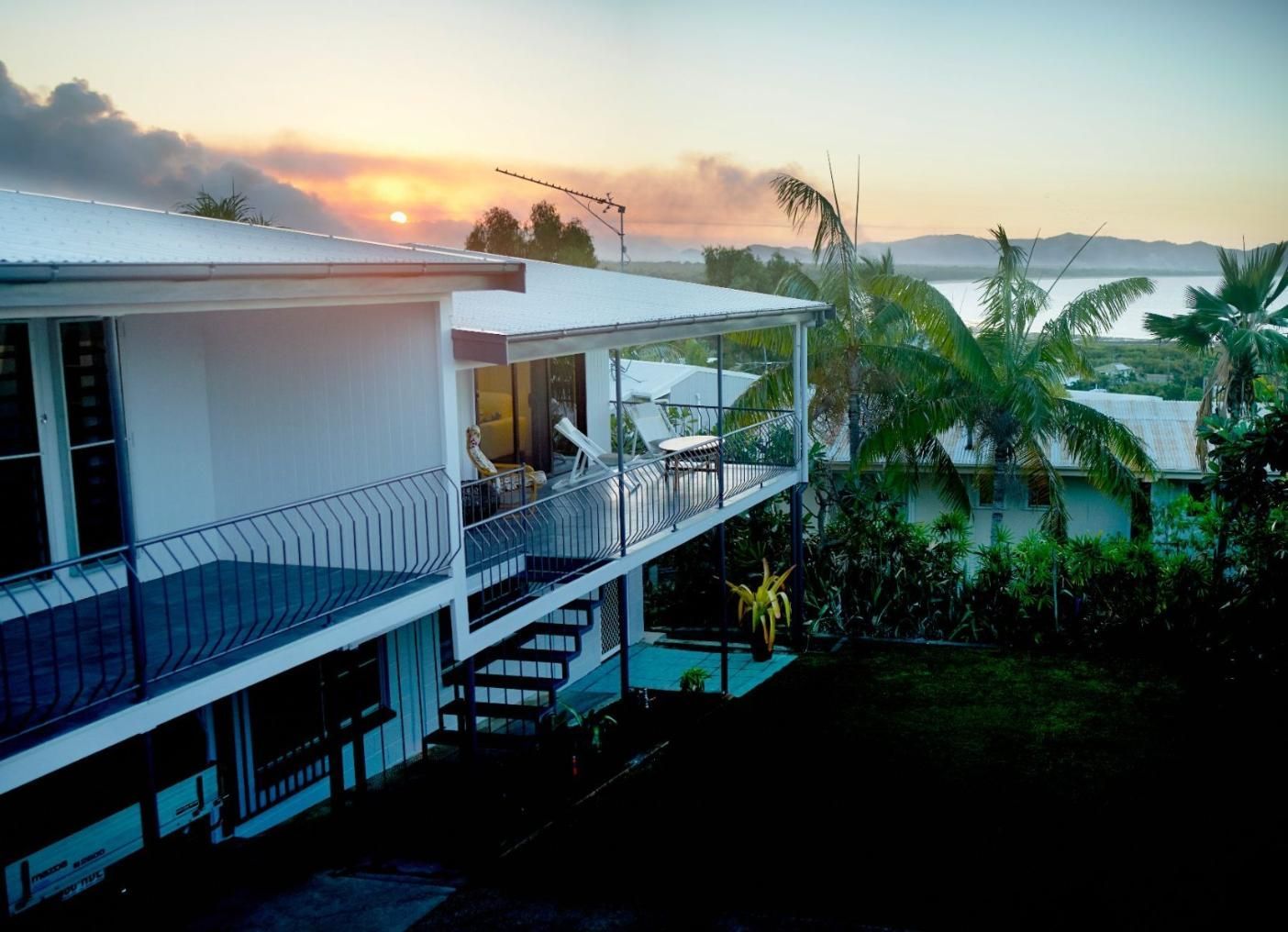 A House With a Balcony Overlooking a Body of Water at Sunset — Pro-Jax Pty Ltd in Bohle, QLD