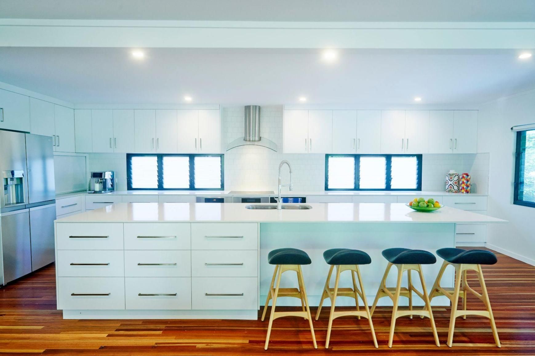 A Kitchen With White Cabinets and Stools and a Large Island — Pro-Jax Pty Ltd in Bohle, QLD