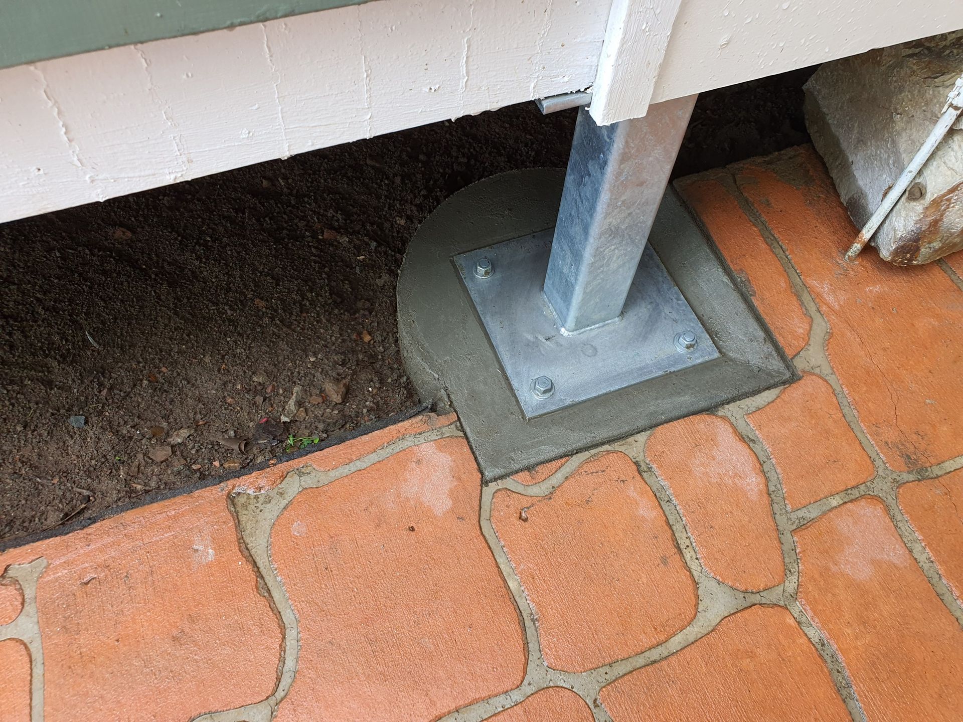 Metal Post Anchored in Concrete, Adjacent to Brick Patio and Soil — Pro-Jax Pty Ltd in Bohle, QLD