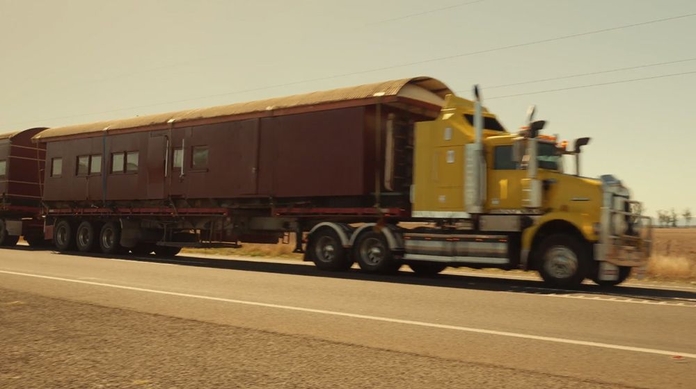 Yellow Semi-truck Hauling a Long, Maroon-coloured Trailer on a Sunny Road — Pro-Jax Pty Ltd in Bohle, QLD