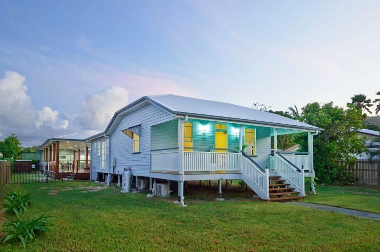 A White House With a Porch and Stairs is Sitting on Top of a Lush Green Lawn — Pro-Jax Pty Ltd in Bohle, QLD