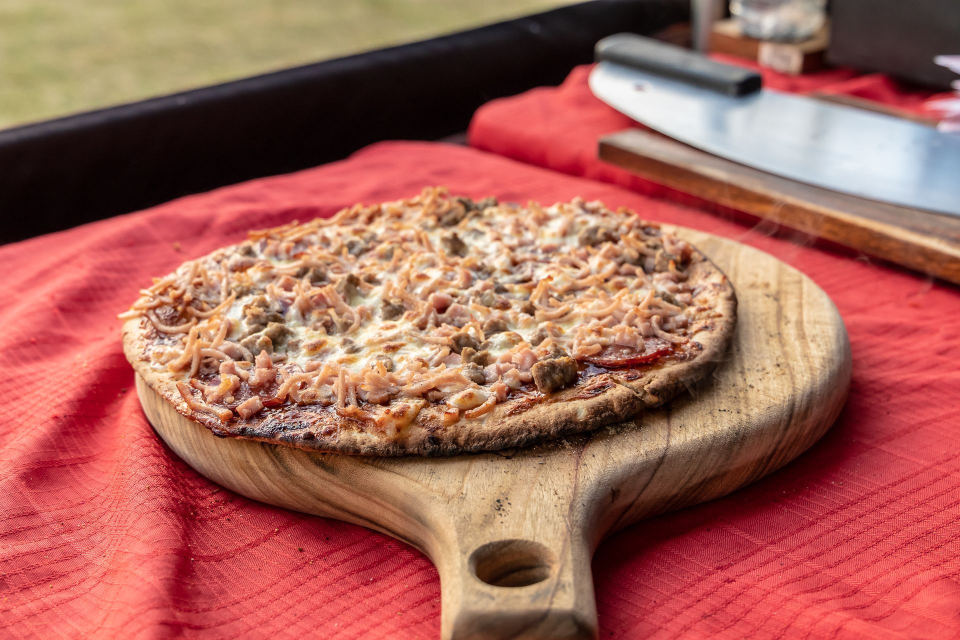 a pizza is sitting on a wooden cutting board on a table .