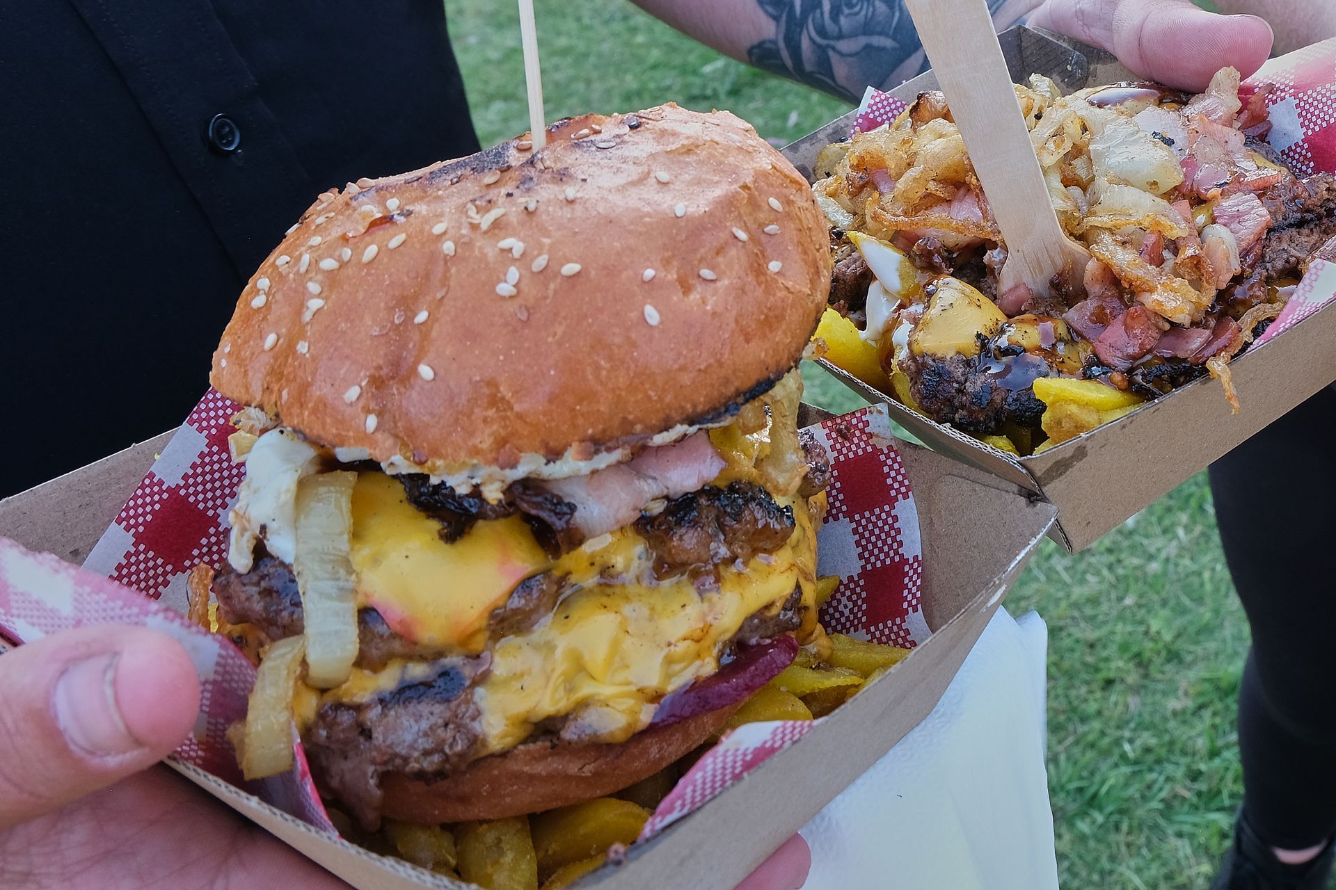 a person is holding a hamburger and french fries in their hands .