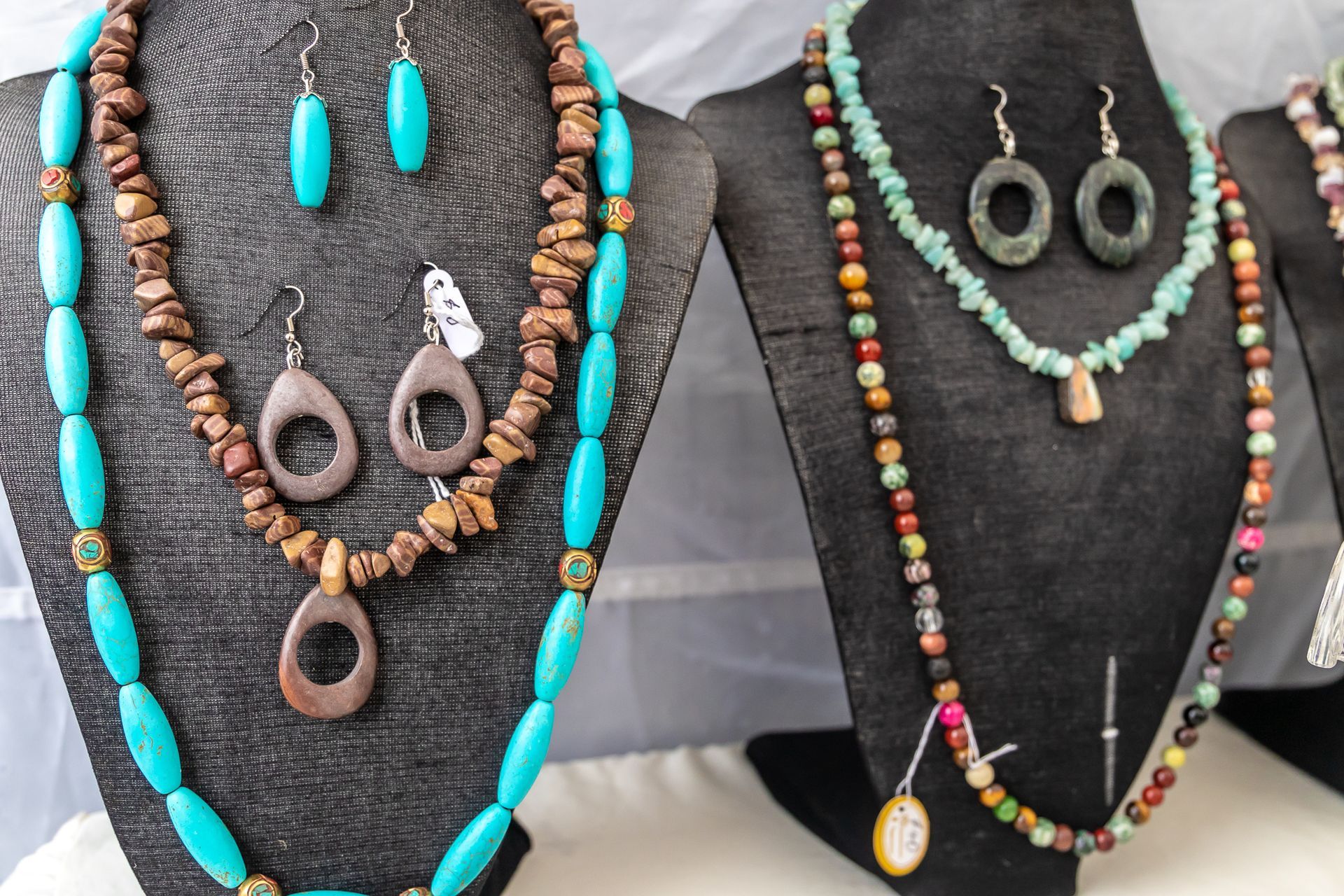 several necklaces and earrings are on display on mannequins