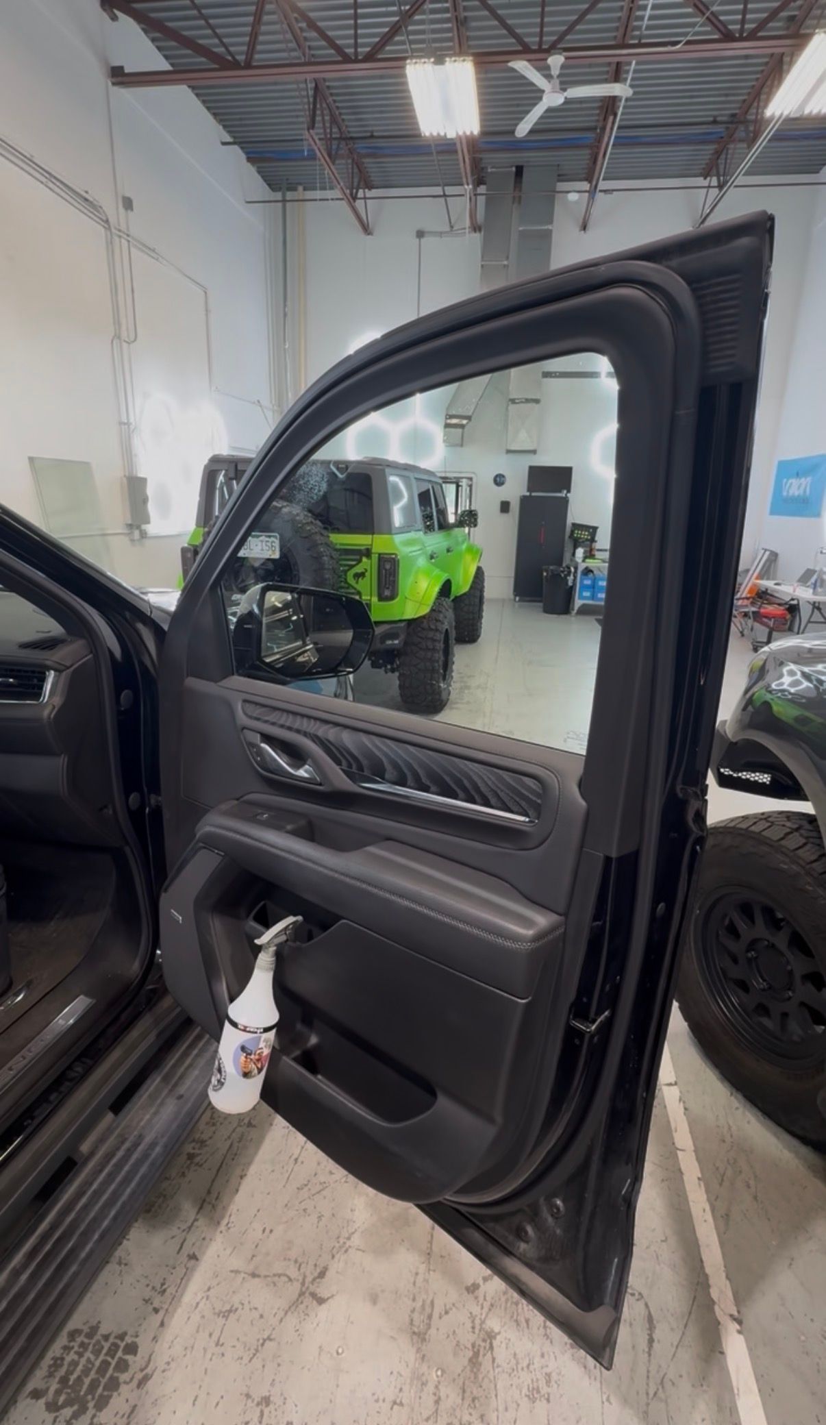 Open truck door in a garage, with a neon yellow vehicle visible through the window.