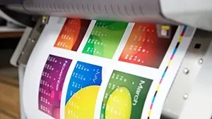 A printer printing a colorful calendar with months displayed, highlighting vibrant hues.