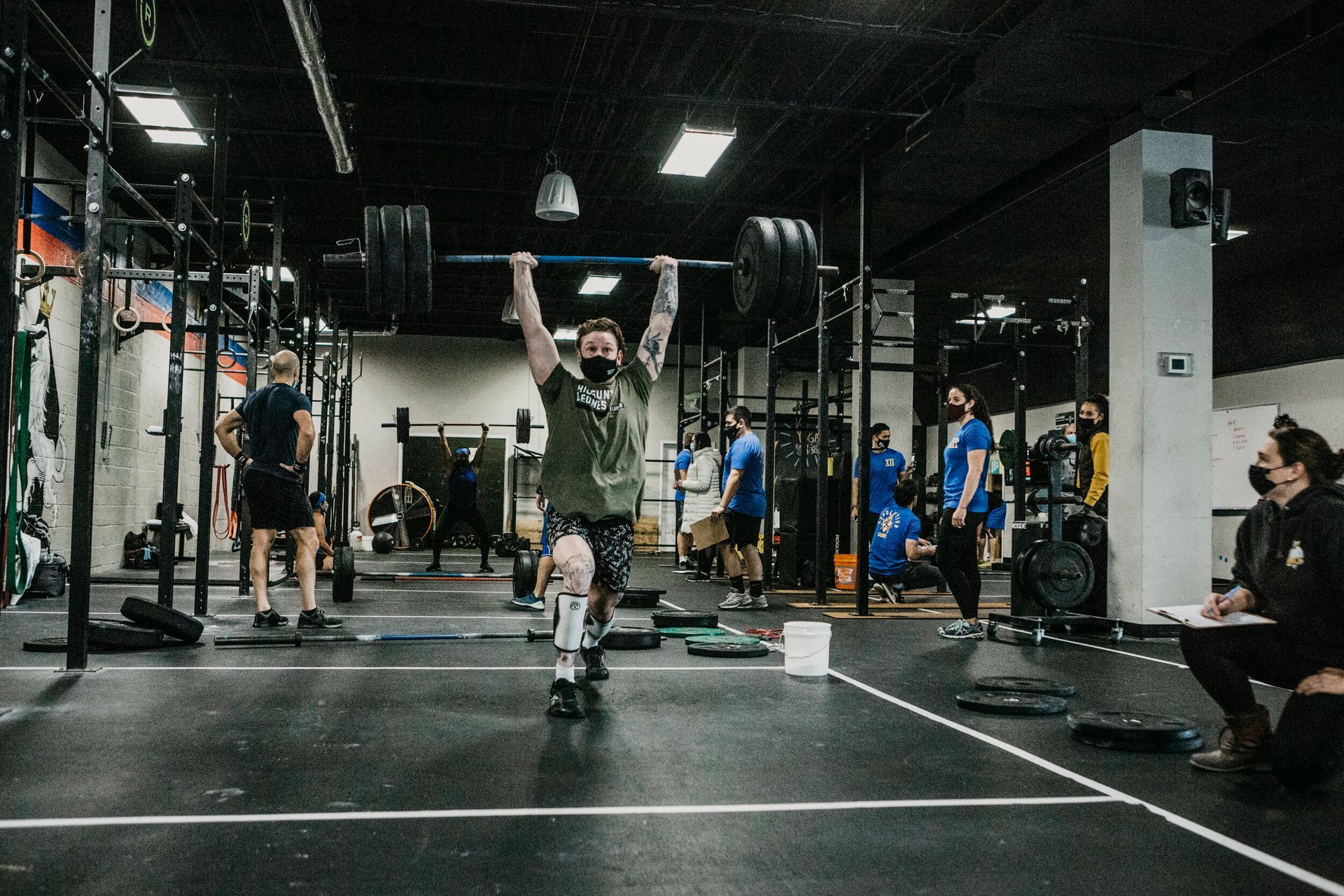 A man is lifting a barbell over his head in a gym.