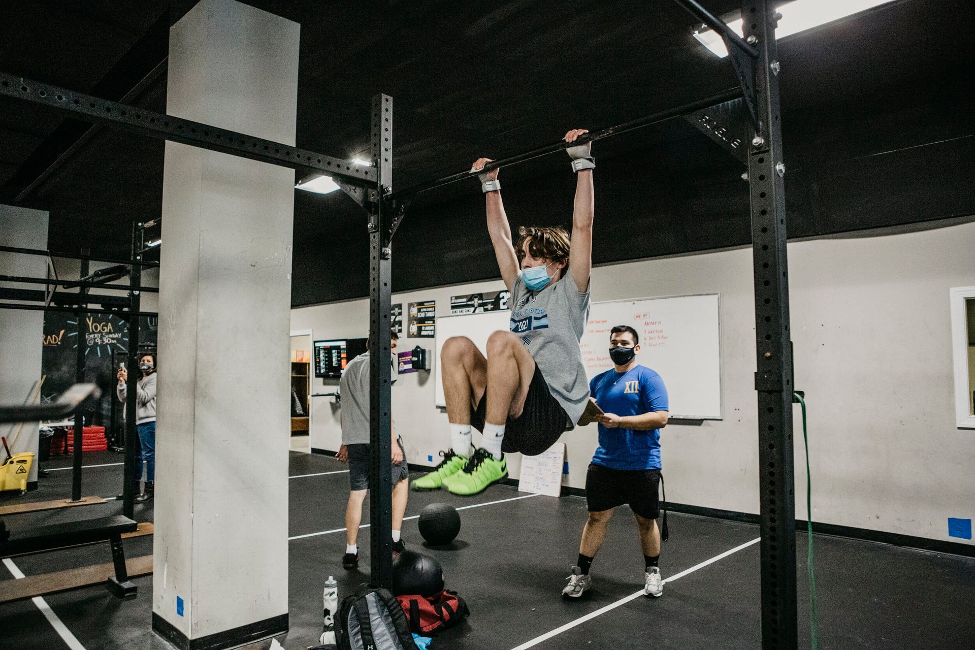 A man is doing a pull up on a bar in a gym.