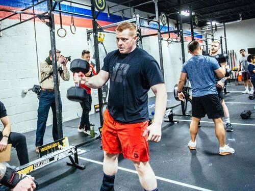 A man is lifting a dumbbell in a gym.