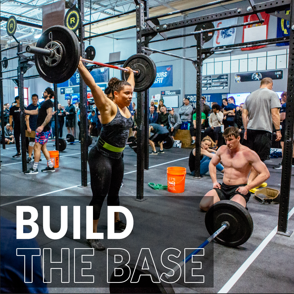 A woman is lifting a barbell in a gym with the words build the base below her