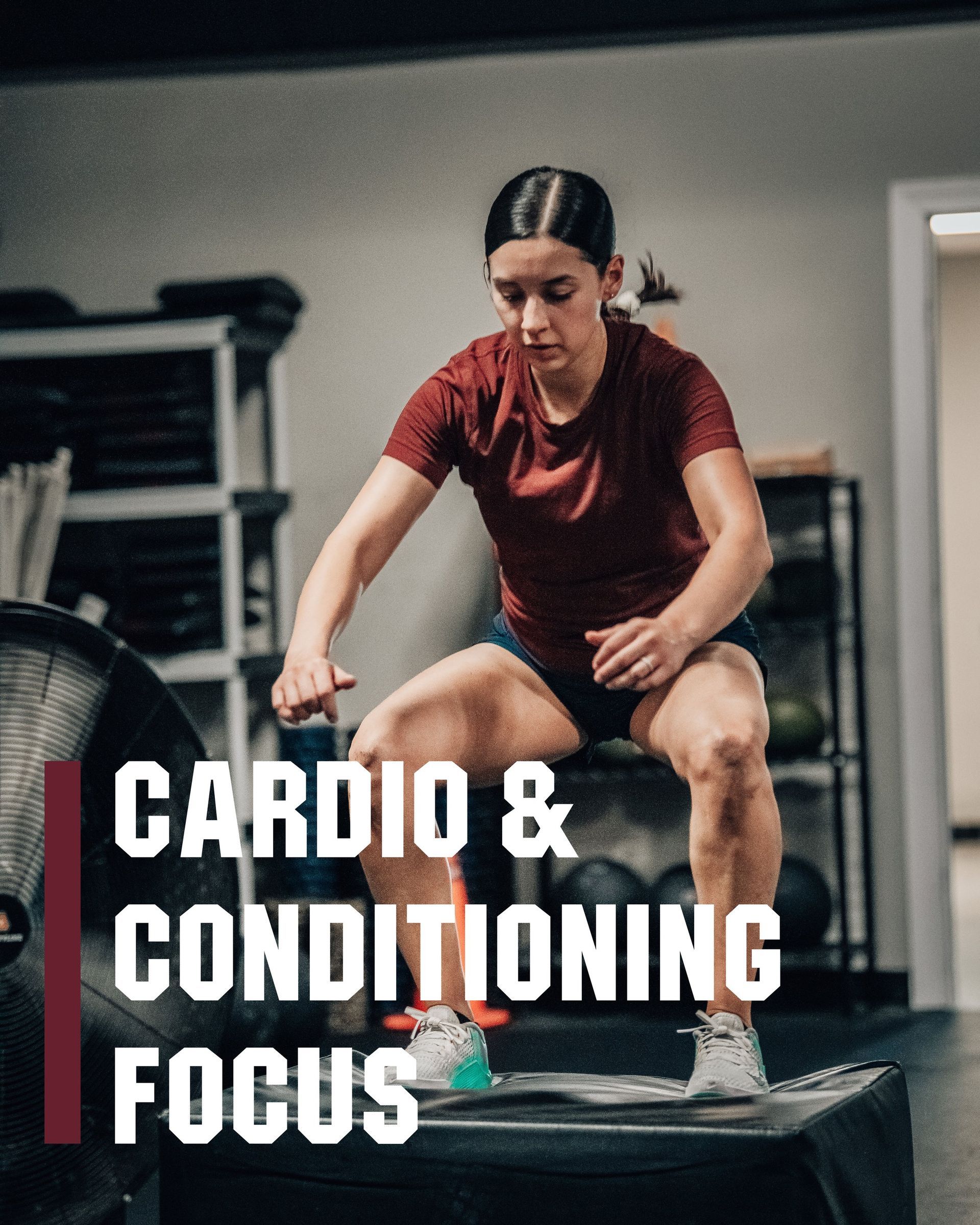 A woman is squatting on a box in a gym.