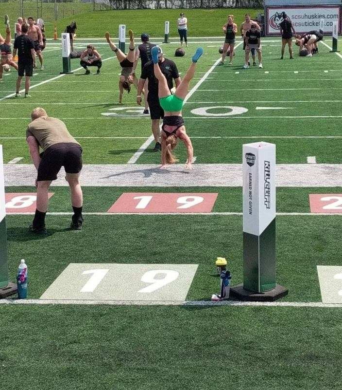 A woman is doing a handstand on a football field