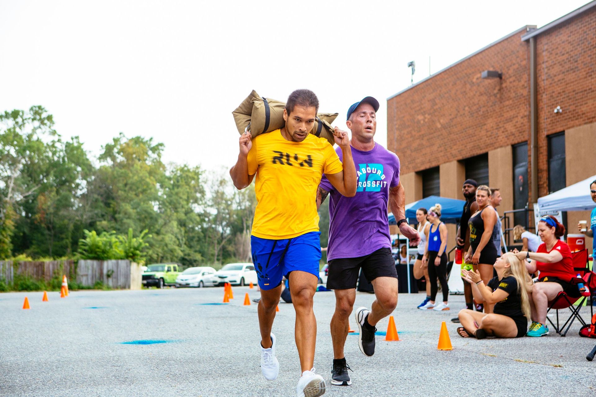 Two men are running with a bag on their backs in a parking lot.