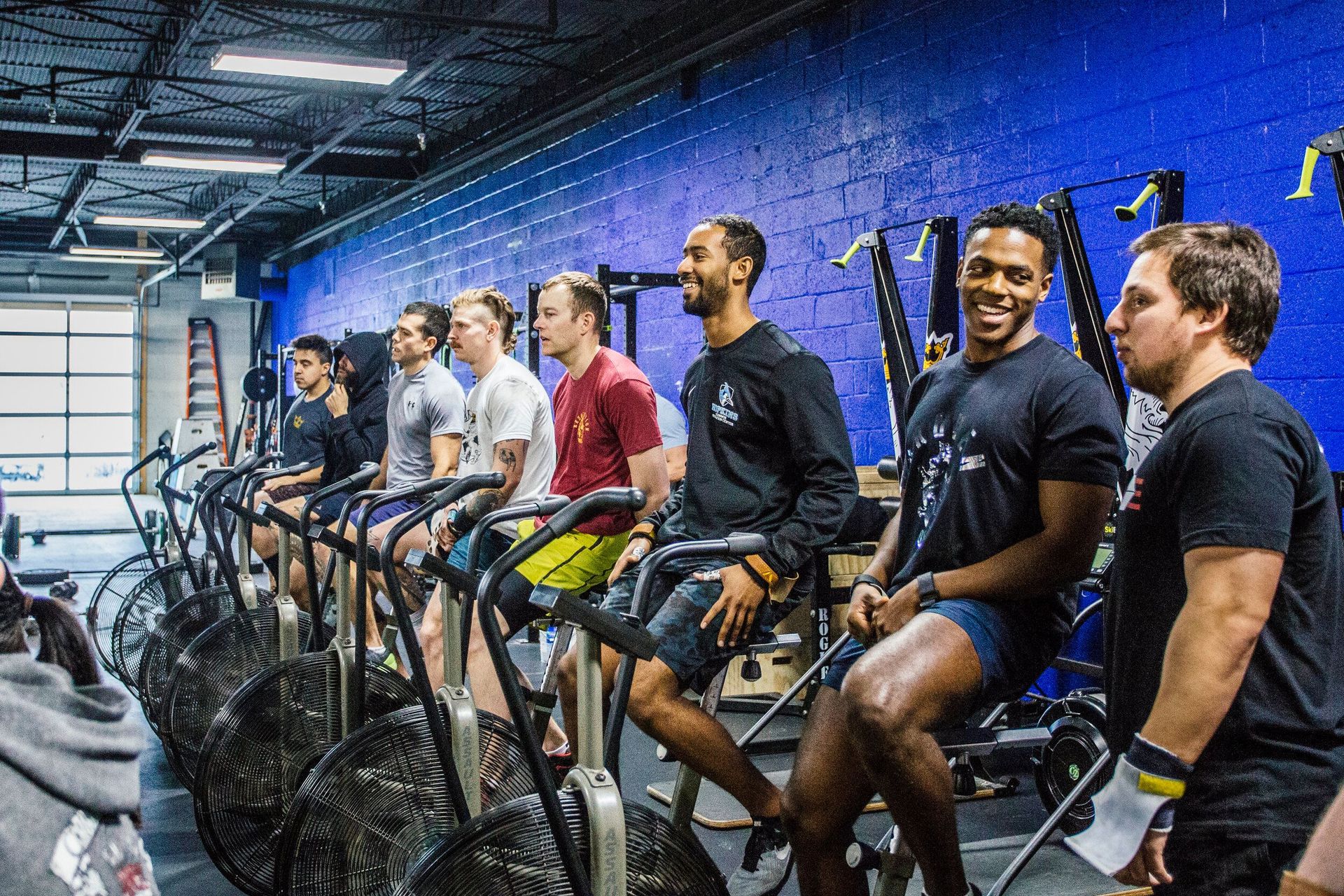 A group of men are riding exercise bikes in a gym.