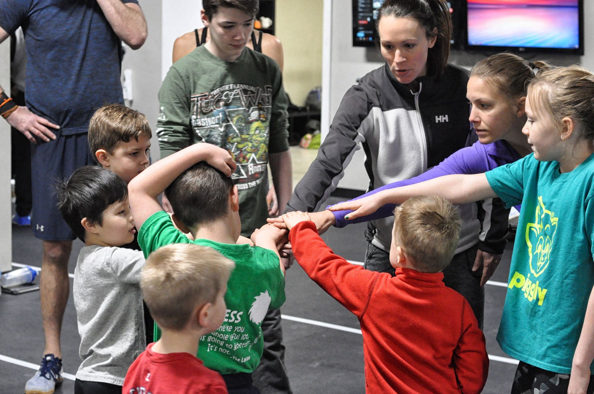 A group of children are putting their hands together in a huddle.