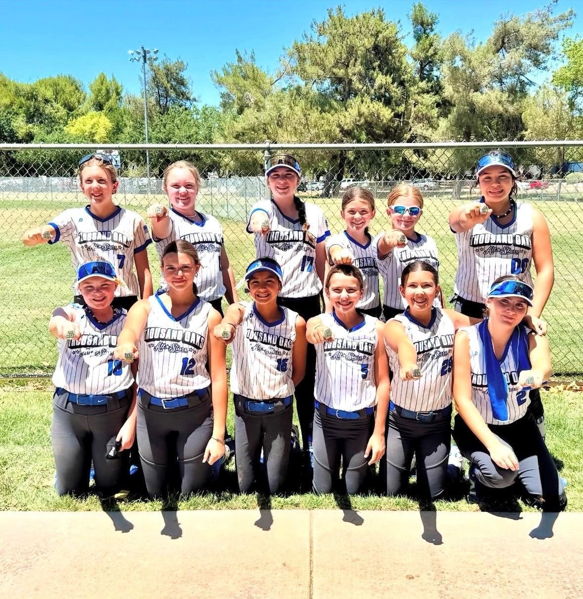 Baseball glove with ball on green grass, with blurred baseballs in the background.