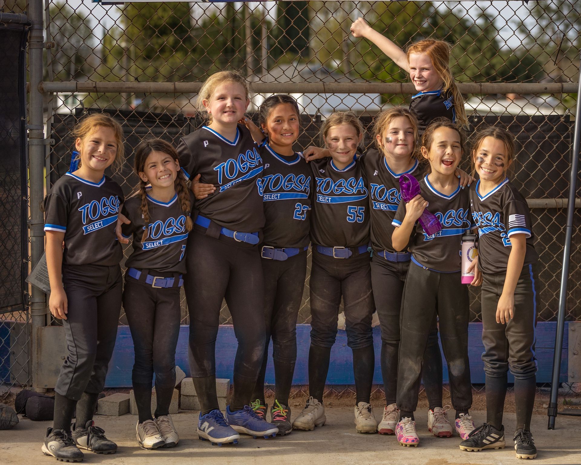 Baseball glove with ball on green grass, with blurred baseballs in the background.