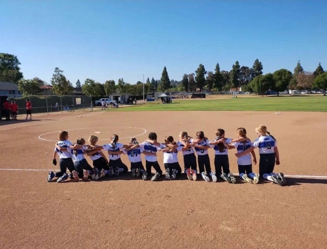 Baseball glove with ball on green grass, with blurred baseballs in the background.