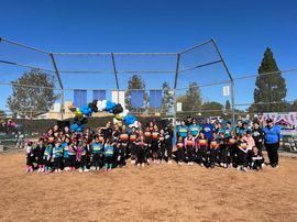 Baseball player sliding into home plate, catcher in front. Blue and gold uniforms, action shot.