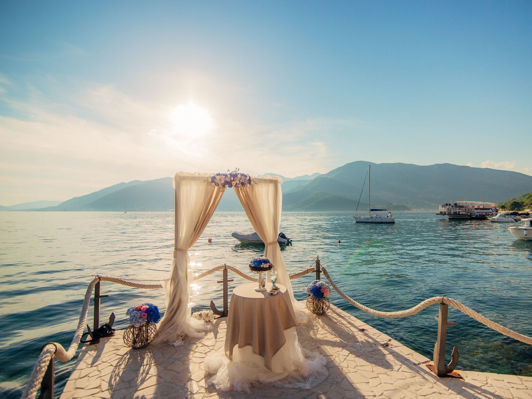 A wedding ceremony is taking place on a dock overlooking the ocean.