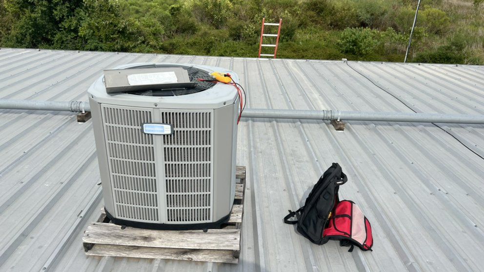 An air conditioner is sitting on a wooden pallet on top of a metal roof.