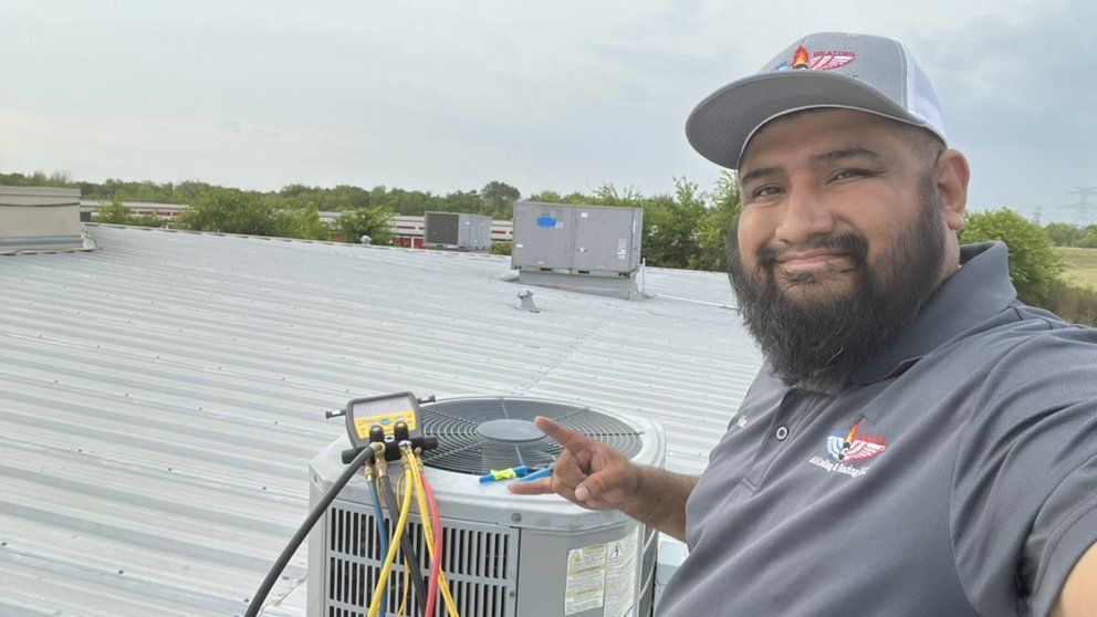 A man with a beard is standing on top of a roof next to an air conditioner.