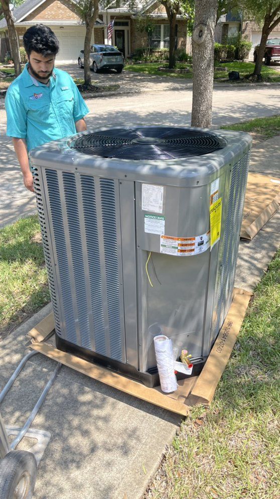 A man is standing next to a large air conditioner on a wooden pallet.