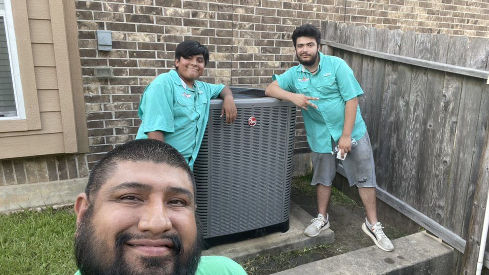 A group of men are standing next to each other in front of an air conditioner.