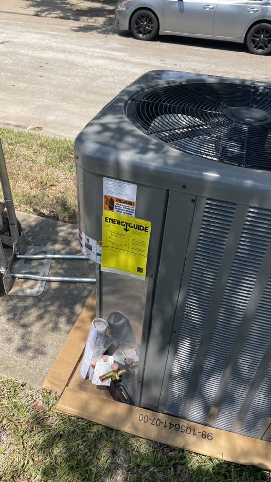 An air conditioner is sitting on top of a cardboard box on the side of the road.