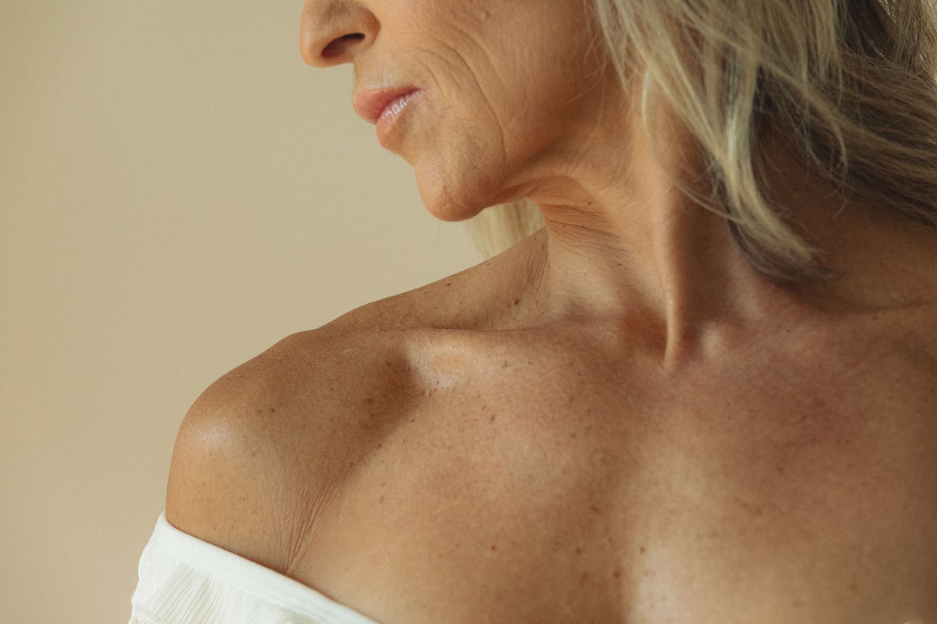A close up of an older woman 's neck and shoulder.