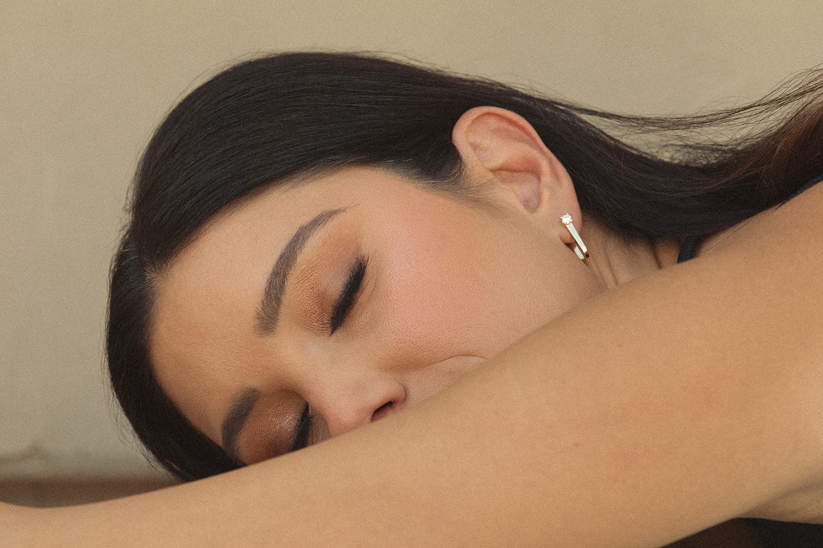 A woman wearing earrings is sleeping with her eyes closed.