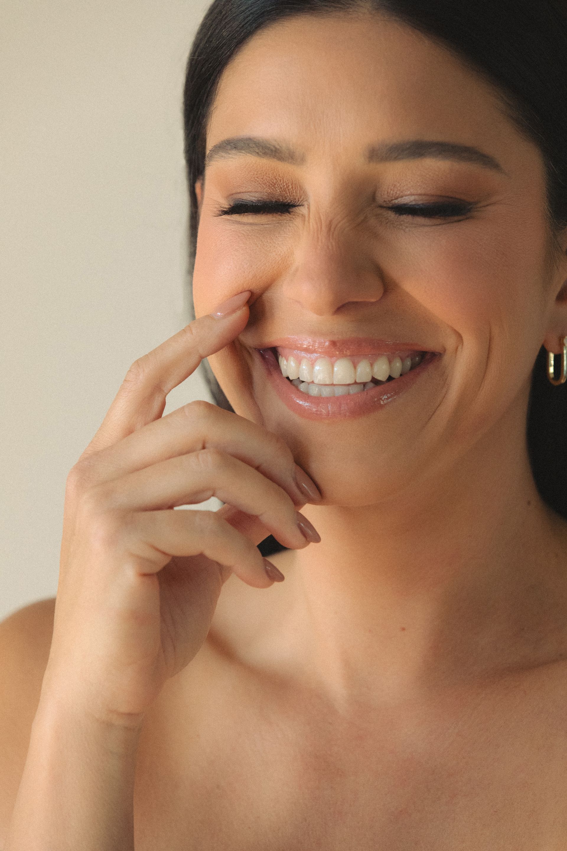 A woman is smiling with her hand on her face.