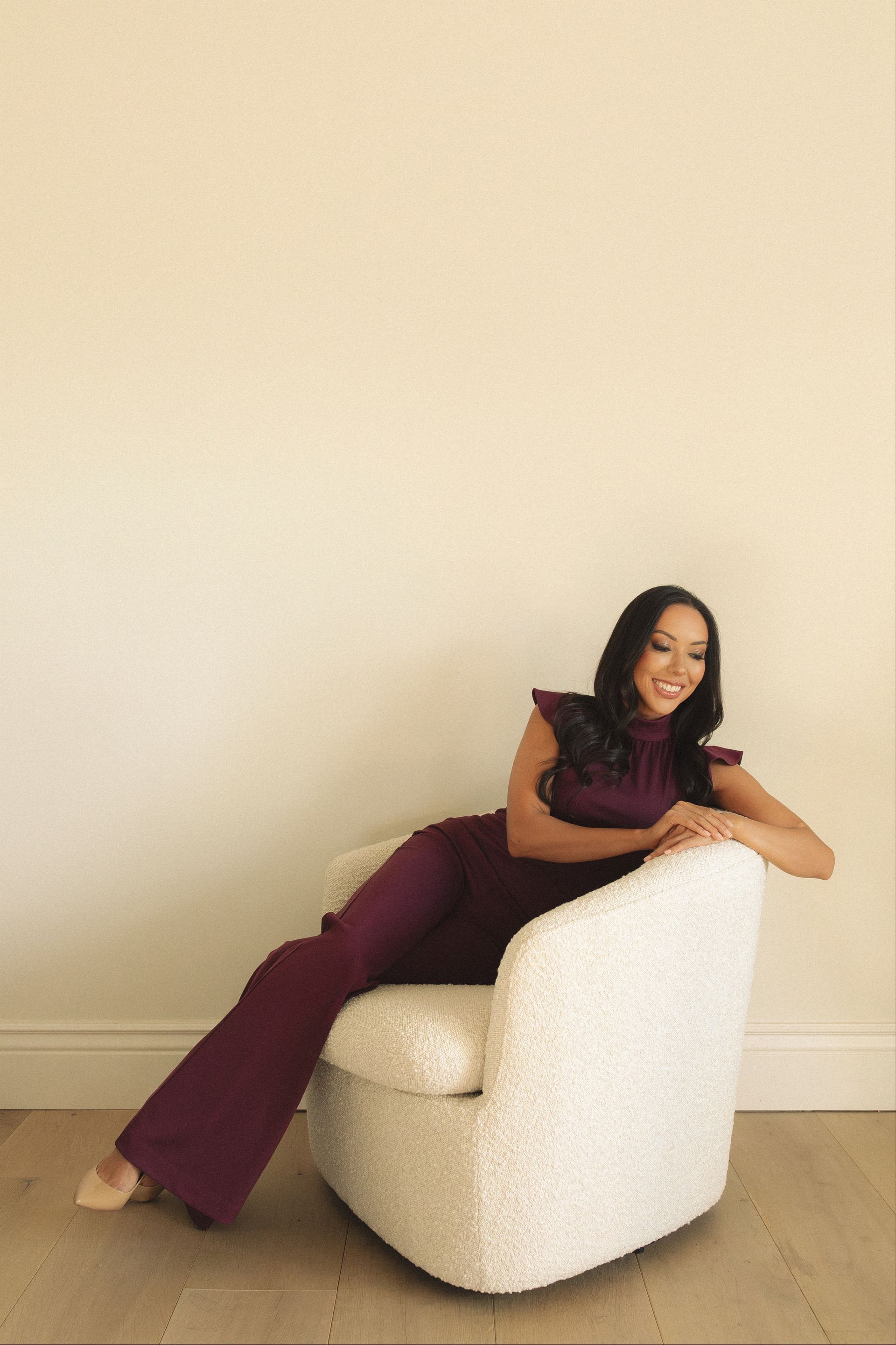 A woman in a purple jumpsuit is sitting in a white chair.