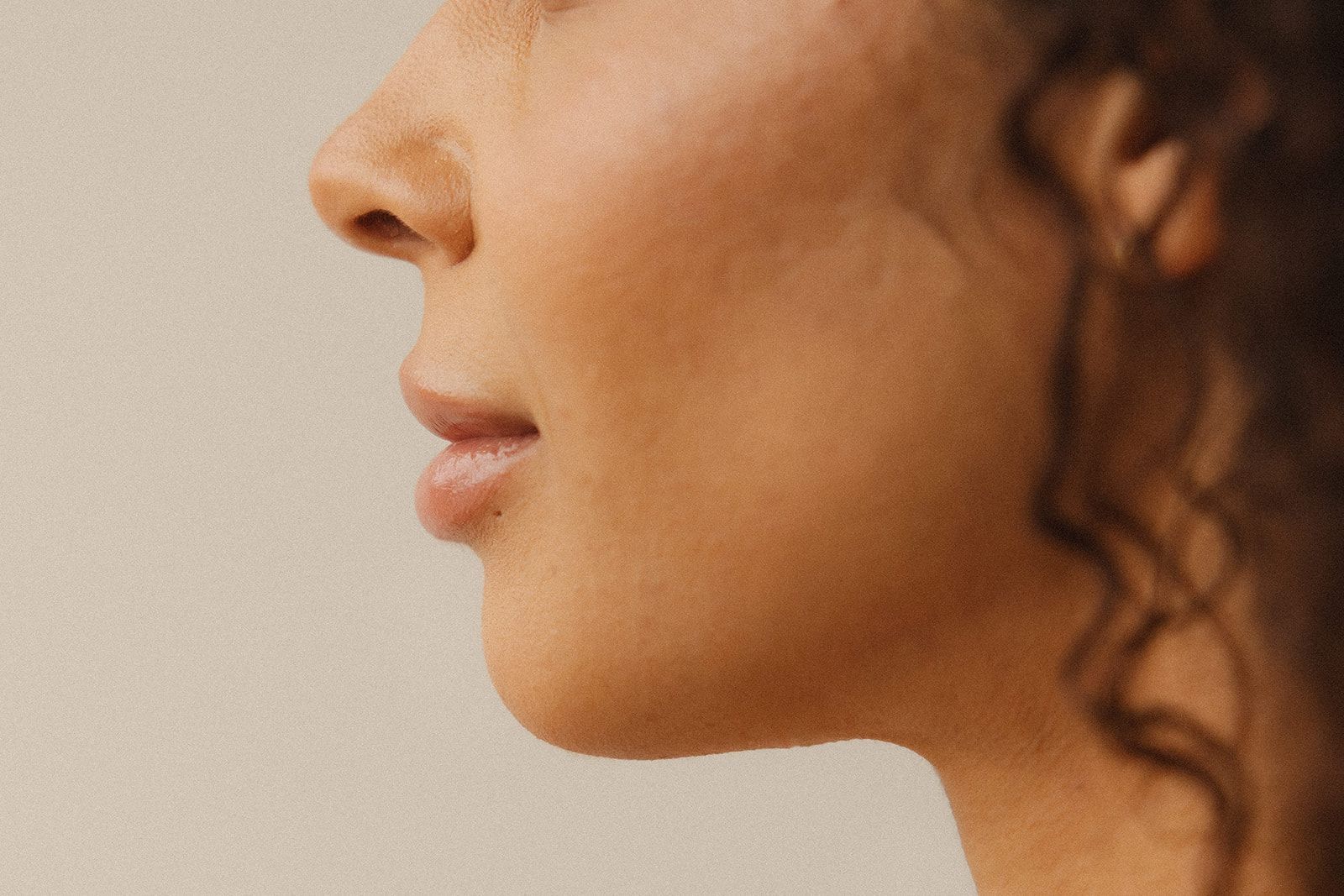 Side profile of a face with natural skin texture against a plain, light background.