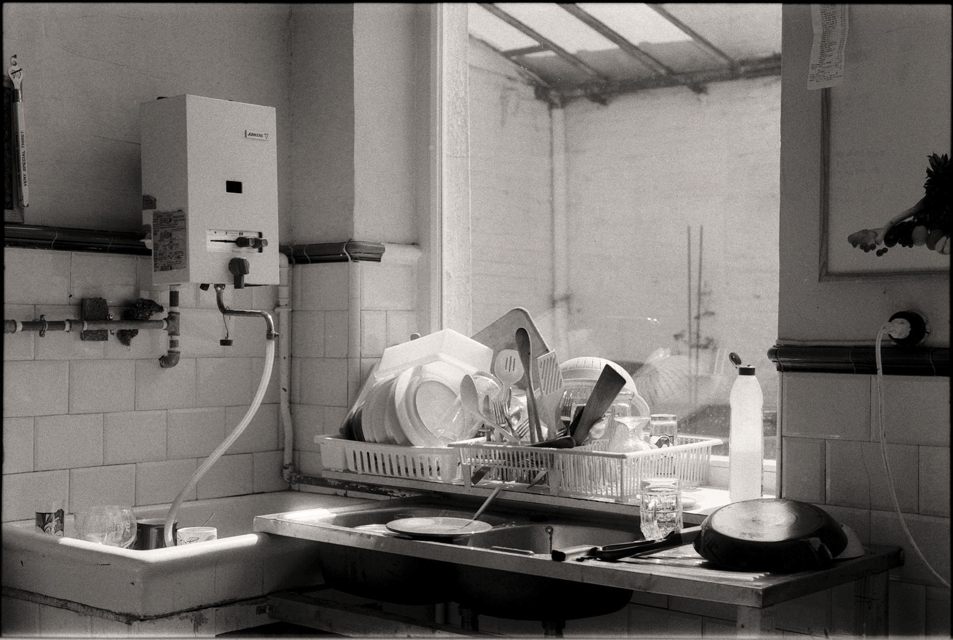 Black-and-white kitchen sink with drying dishes, a countertop, and a water heater on the wall.