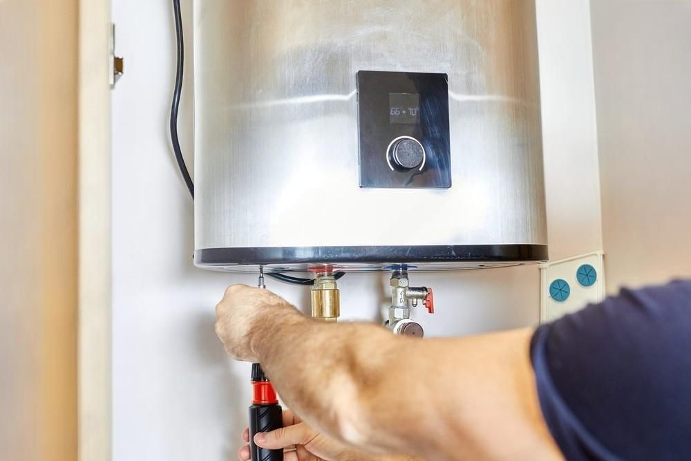 Person adjusting controls on a silver water heater in a home utility area