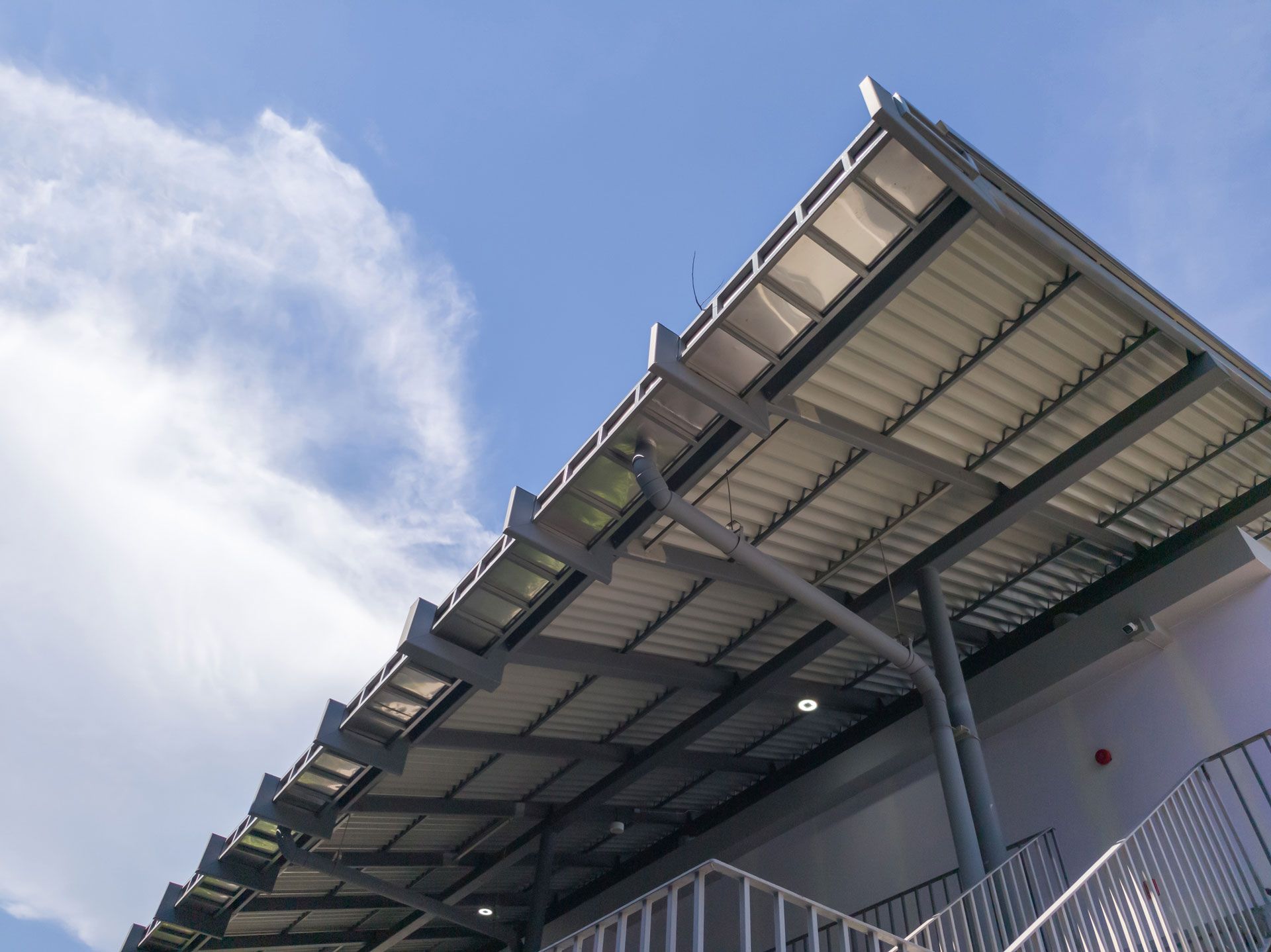 Metal roof of a building against a partly cloudy blue sky.