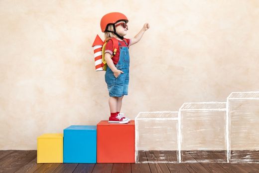 Young child with backpack climbing play blocks during therapy activity at The Skills Lab